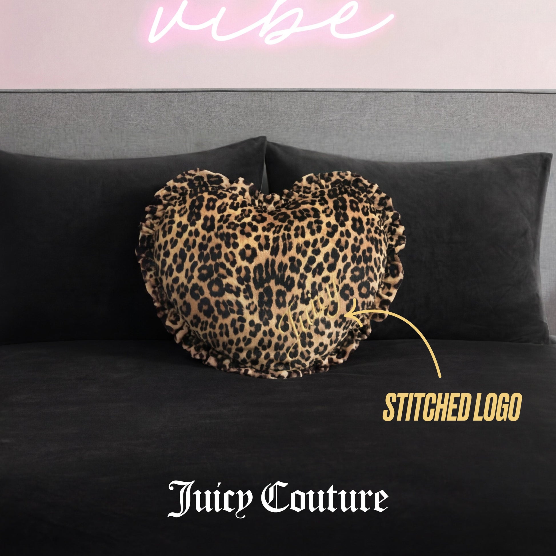 A Heart Shaped Decorative Pillow with cheetah print and ruffled edges sits on a black bed with a gray headboard. A stitched logo is visible, and "Juicy Couture" appears at the bottom of the image.