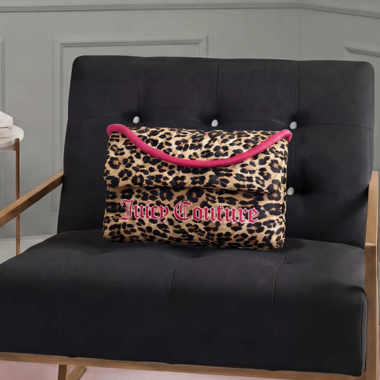 A Purse Decorative Pillow with leopard print, pink trim, and bold Juicy Couture lettering adds a trendy touch to a modern black armchair with wooden armrests in a stylish room.