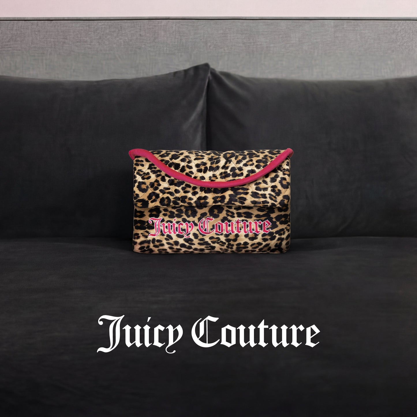 A Juicy Couture Purse Decorative Pillow with leopard print and pink trim accents a dark gray velvet couch. The white Gothic "Juicy Couture" logo appears at the image's bottom, adding trendy flair.