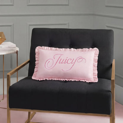 A black tufted chair with gold arms holds a Ruffle Decorative Pillow—a pink accent pillow with "Juicy" in rhinestones—set against a gray paneled wall.
