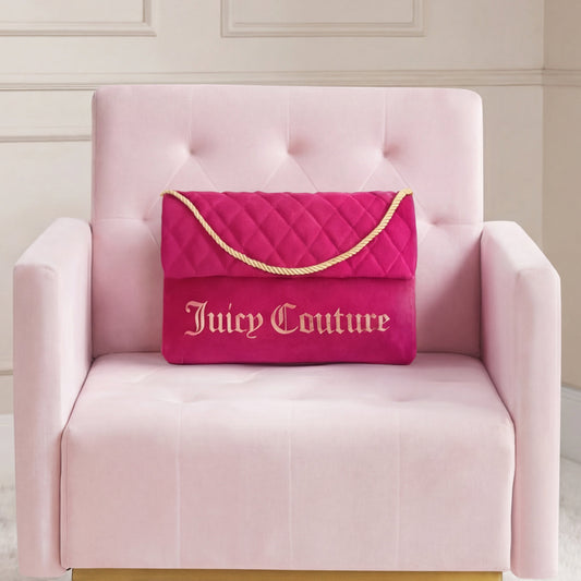 A Purse Decorative Pillow is paired with a bright pink Juicy Couture quilted bag on a pale pink armchair, set against a neutral paneled wall for a trendy accent.