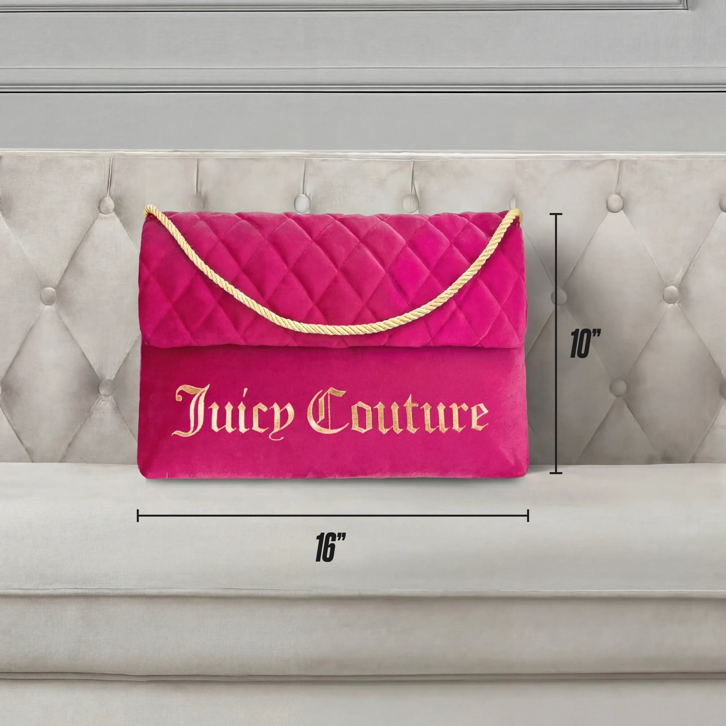 The Purse Decorative Pillow, in pink quilted fabric with gold lettering and a rope handle, measures 16" wide by 10" tall. Shown on a beige tufted couch, it adds a trendy accent to any space.