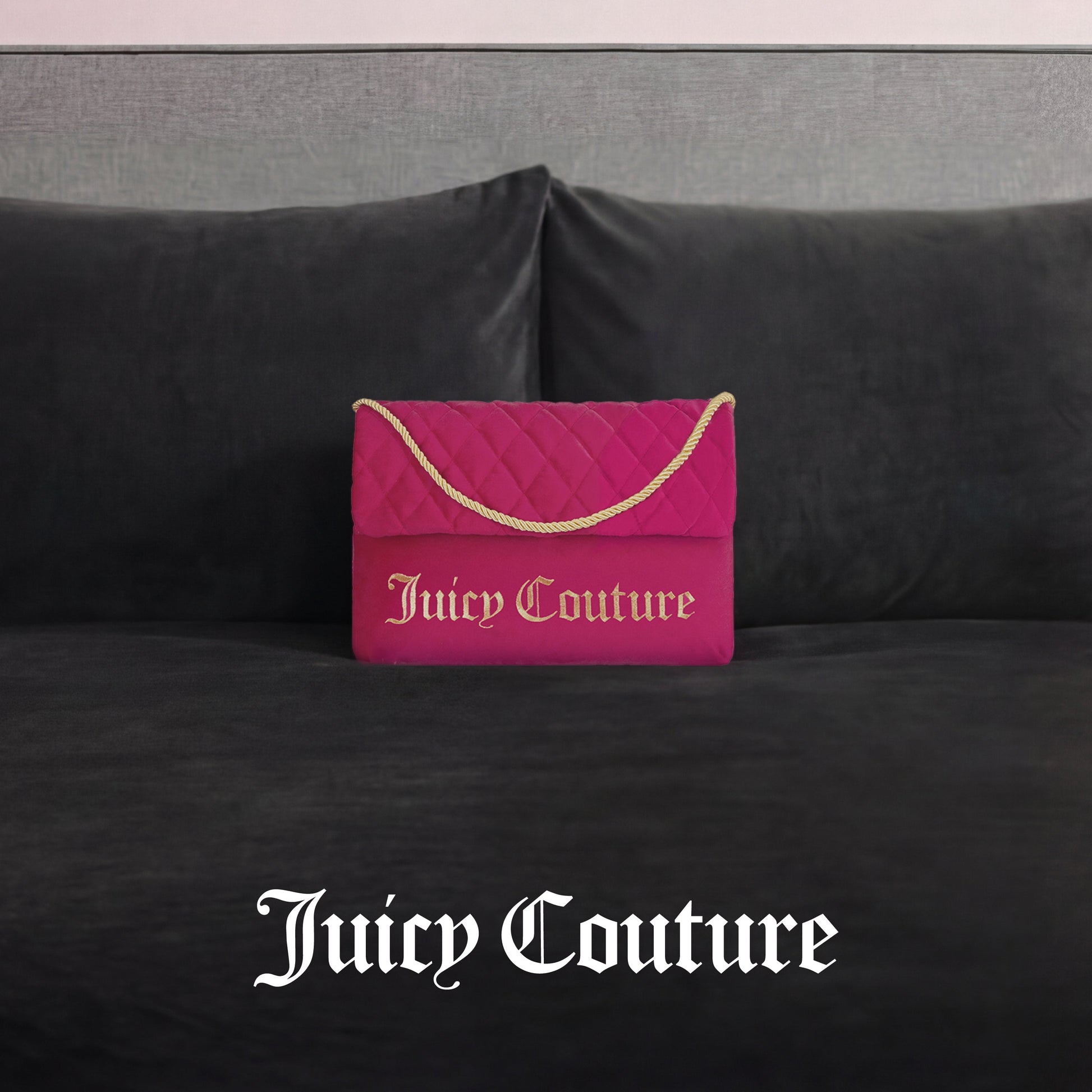 The Purse Decorative Pillow, styled like a pink quilted Juicy Couture handbag with a gold chain and logo, adds a trendy accent to any dark gray velvet couch. "Juicy Couture" is displayed in white text below.