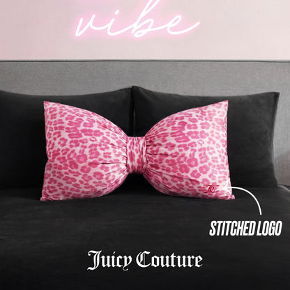 A Bow Decorative Pillow with pink cheetah print and a stitched Juicy Couture logo rests on a dark gray couch, with "vibe" in pink neon above and text highlighting the logo.