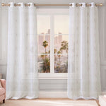 Two sheer white Vertical Bow Ribbon Sheer Window Curtains with a subtle loop pattern hang from a gold curtain rod in front of a window. Palm trees and a city skyline are visible outside. A blush pink chair is partially visible on the left.