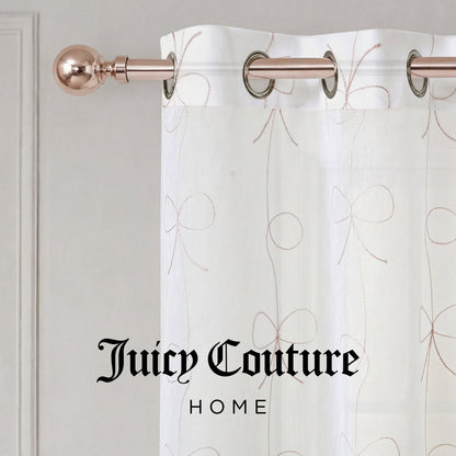 A sheer white Vertical Bow Ribbon Sheer Window Curtain featuring a delicate bow pattern drapes elegantly from a metallic rod, bringing a touch of sophistication to any room. Ideal as Juicy Couture window curtains, this stylish panel is adorned with the words "Juicy Couture HOME" printed in black at the bottom.