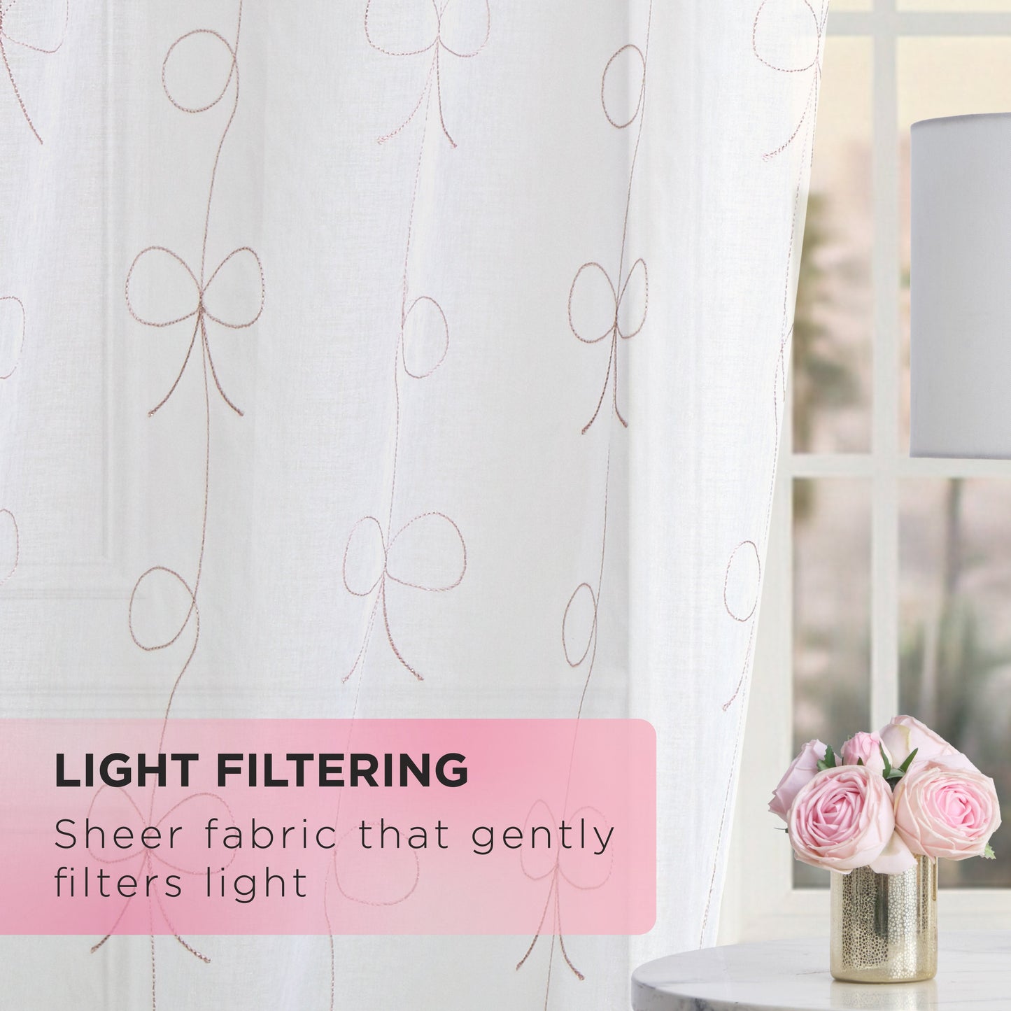 A sheer white Vertical Bow Ribbon Sheer Window Curtain by Juicy Couture, featuring a delicate bow pattern, gently filters incoming sunlight. Nearby, a table with pink roses in a vase adds a touch of elegance. The text reads: “LIGHT FILTERING: Sheer fabric that gently filters light.”.