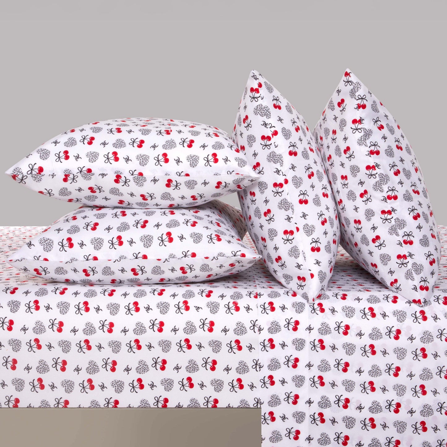 Four pillows and a sheet with a white background and red and black bee patterns are neatly arranged. This Microfiber Sheet Set With Extra Pillowcases features a playful, whimsical insect design, adding a cheerful atmosphere to your room while providing luxurious comfort for your bedding.