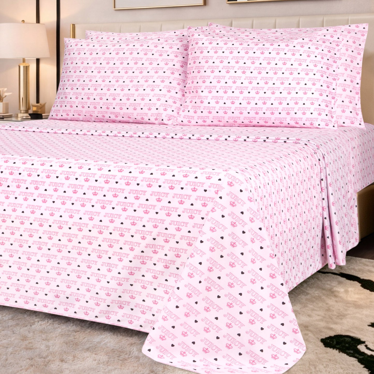 A modern bedroom with a beige headboard, nightstand, and lamp is styled with the Microfiber Sheet Set With Extra Pillowcases in ultra-soft, light pink fabric featuring small cute icons and diagonal text.