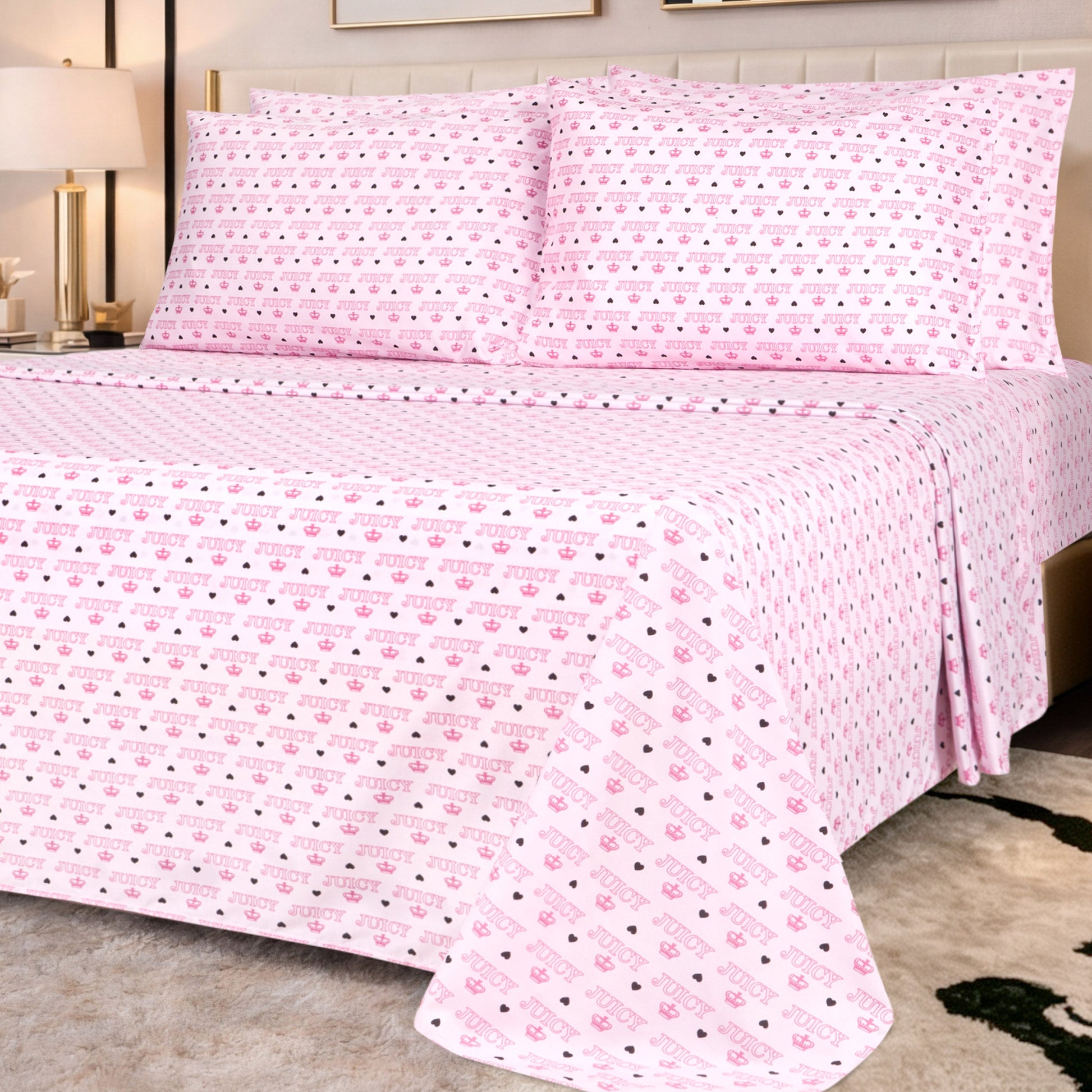 A modern bedroom with a beige headboard, nightstand, and lamp is styled with the Microfiber Sheet Set With Extra Pillowcases in ultra-soft, light pink fabric featuring small cute icons and diagonal text.