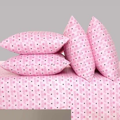 Four pink pillows and the "Microfiber Sheet Set With Extra Pillowcases," featuring an ultra-soft microfiber fabric adorned with a repeating pattern of hearts and the word "love" in red and purple, are arranged neatly on a bed against a plain gray background—creating the signature style of Juicy Couture bedding.