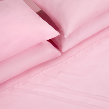 A close-up view of a neatly folded Microfiber Sheet Set With Extra Pillowcases, featuring pink bed sheets and pillowcases arranged on a matching pink bedspread, showcasing the essence of luxury bedding.