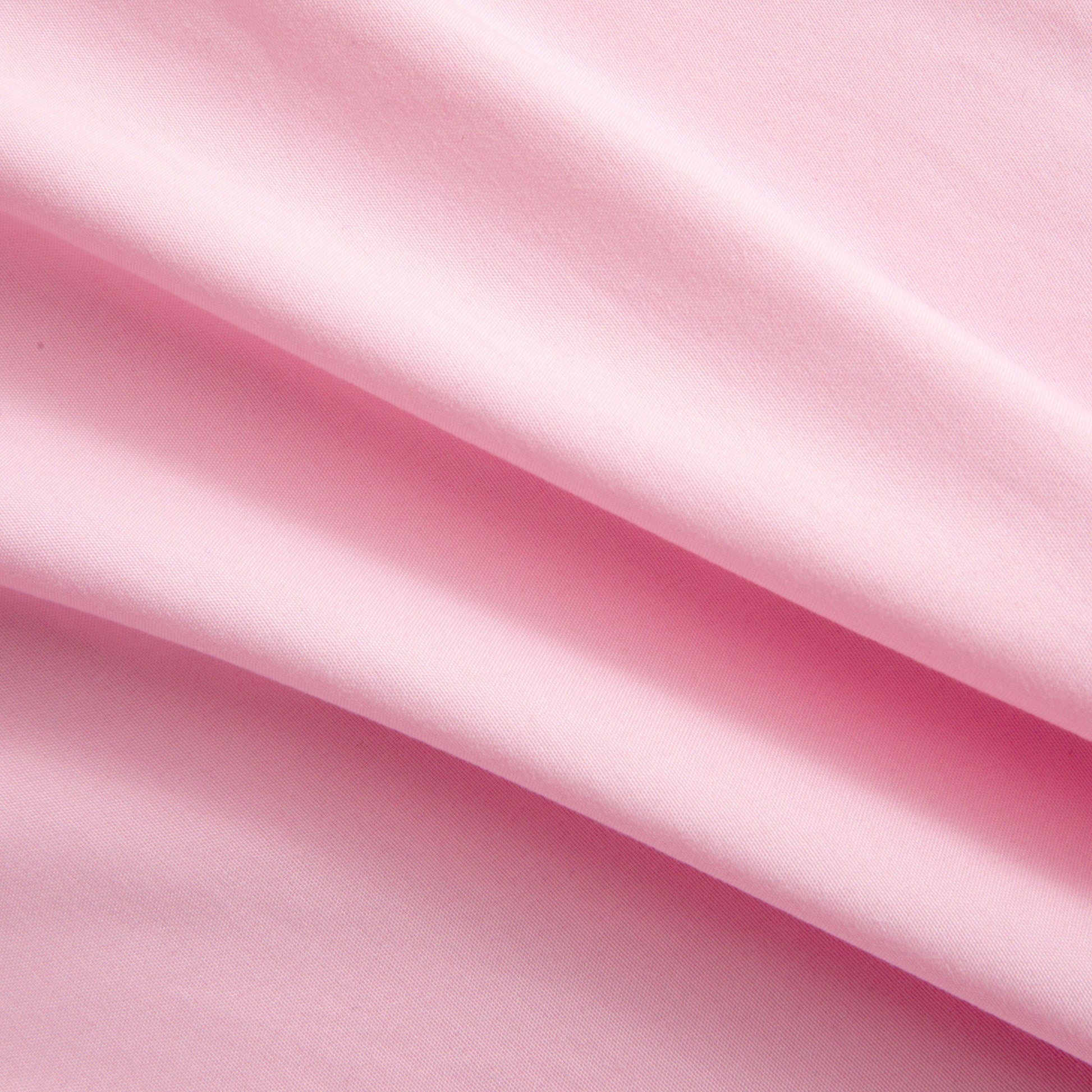 Close-up of soft pink microfiber fabric from the Microfiber Sheet Set With Extra Pillowcases, featuring gentle folds and a smooth texture that evoke the feel of luxury bedding, with light and shadow highlighting its elegant surface.