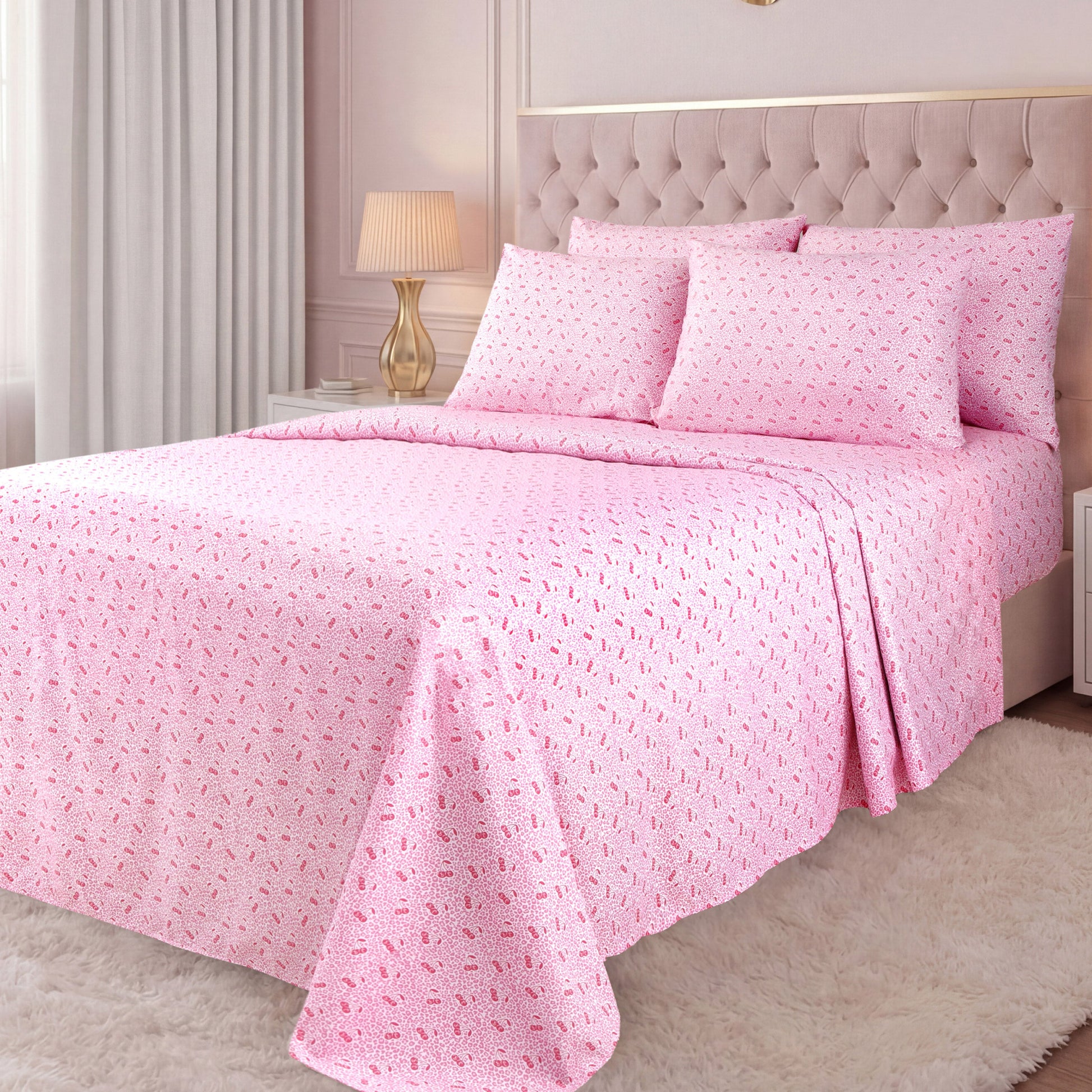 A neatly made bed features a light pink patterned bedspread and matching pillows, complemented by the Microfiber Sheet Set With Extra Pillowcases, all set against a tufted beige headboard in a softly lit bedroom with white curtains, a nightstand, and a table lamp.