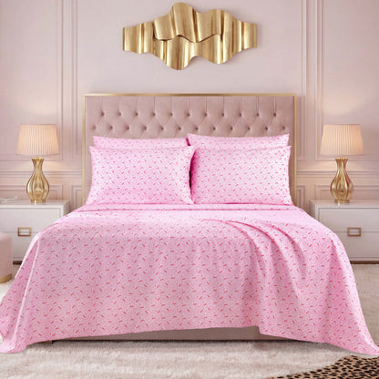 A neatly made bed dressed in a pink patterned Microfiber Sheet Set With Extra Pillowcases and two matching pillows, flanked by white nightstands with gold lamps, sits in an elegant room adorned with a gold wall decoration above the headboard.