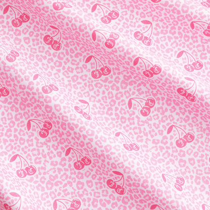 Bring a playful yet sophisticated touch to your bedroom with the Microfiber Sheet Set With Extra Pillowcases, featuring soft pink fabric adorned with a light pink leopard print and darker pink cherry illustrations arranged in a repeating diagonal pattern across the surface.
