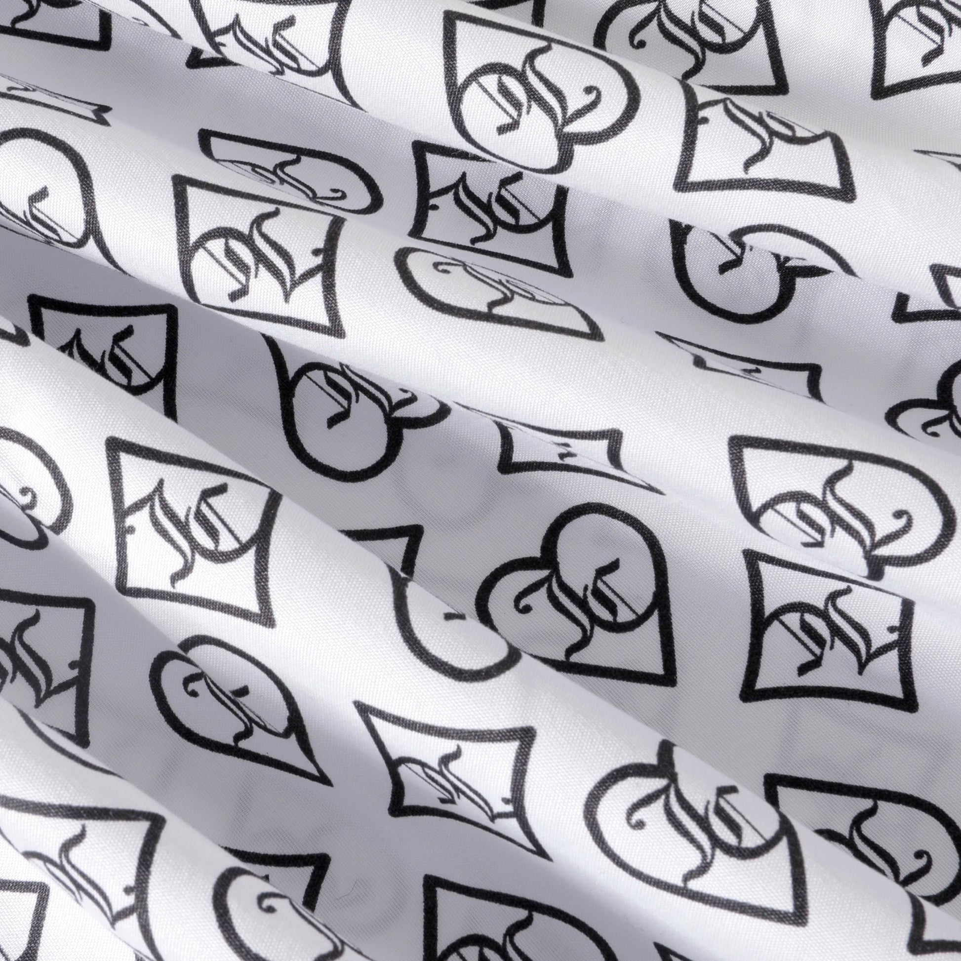 Crafted from soft microfiber, the Microfiber Sheet Set With Extra Pillowcases showcases a white fabric adorned with a repeating black pattern of hearts and diamonds, each featuring a stylized symbol or logo. Reminiscent of designer luxury bedding, this set's slightly wrinkled texture creates gentle shadows and adds visual interest to the patterned surface.