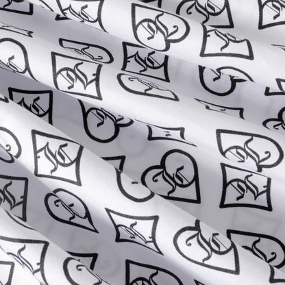 Crafted from soft microfiber, the Microfiber Sheet Set With Extra Pillowcases showcases a white fabric adorned with a repeating black pattern of hearts and diamonds, each featuring a stylized symbol or logo. Reminiscent of designer luxury bedding, this set's slightly wrinkled texture creates gentle shadows and adds visual interest to the patterned surface.