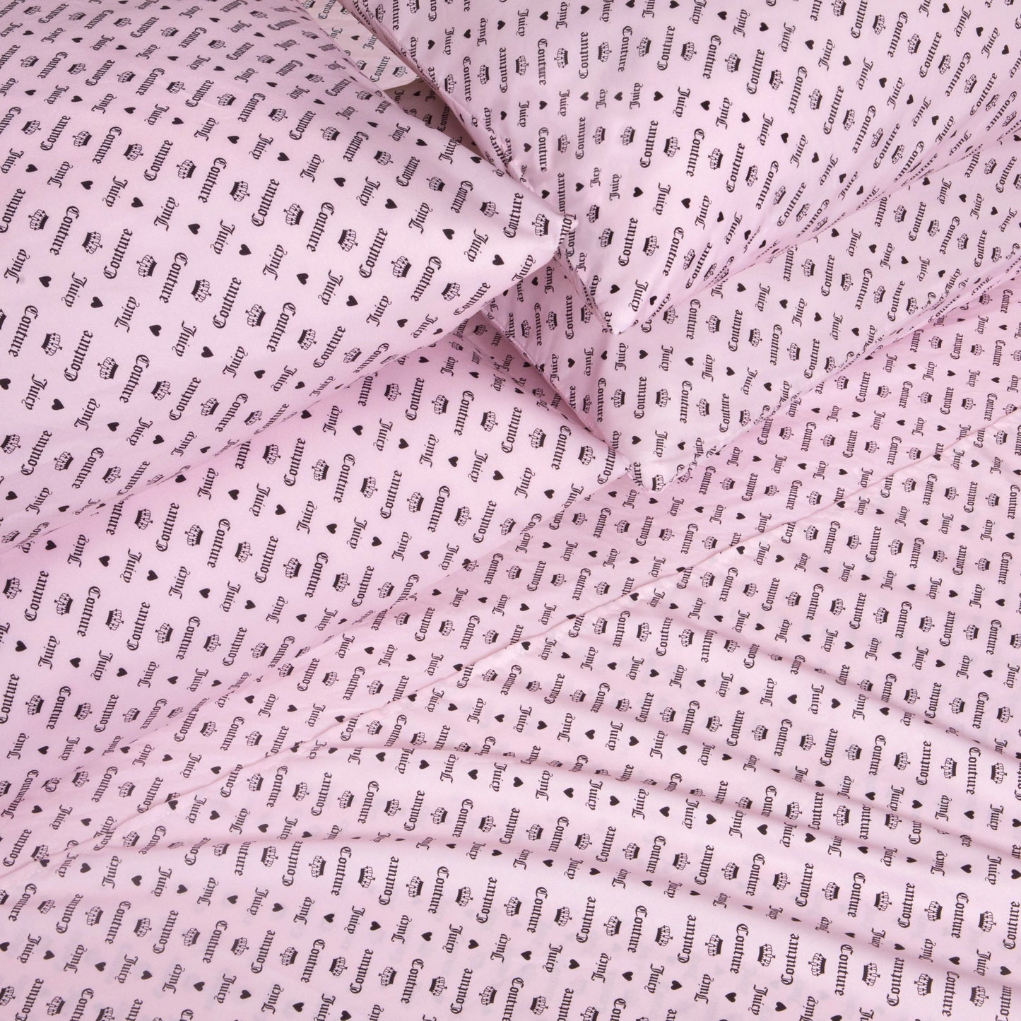 The Microfiber Sheet Set With Extra Pillowcases, featuring pink bed sheets and pillowcases adorned with a repeating black “Gucci” wordmark and logo pattern, is neatly arranged to create an eye-catching, luxurious look for any bedroom. This set delivers a fashionable flair that rivals the chic style of a Juicy Couture sheet set.