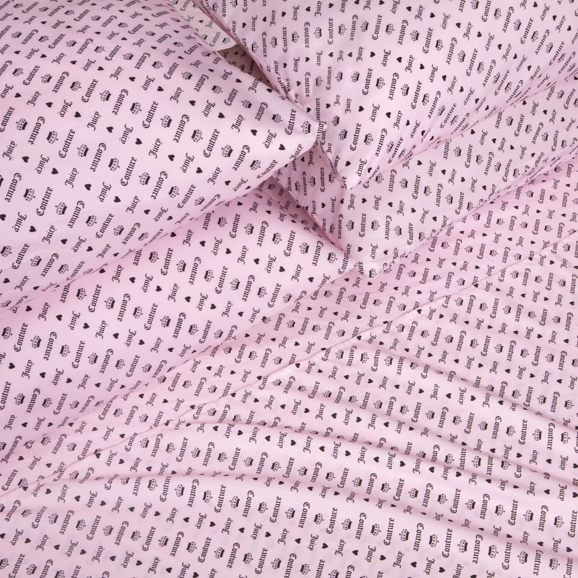 The Microfiber Sheet Set With Extra Pillowcases, featuring pink bed sheets and pillowcases adorned with a repeating black “Gucci” wordmark and logo pattern, is neatly arranged to create an eye-catching, luxurious look for any bedroom. This set delivers a fashionable flair that rivals the chic style of a Juicy Couture sheet set.