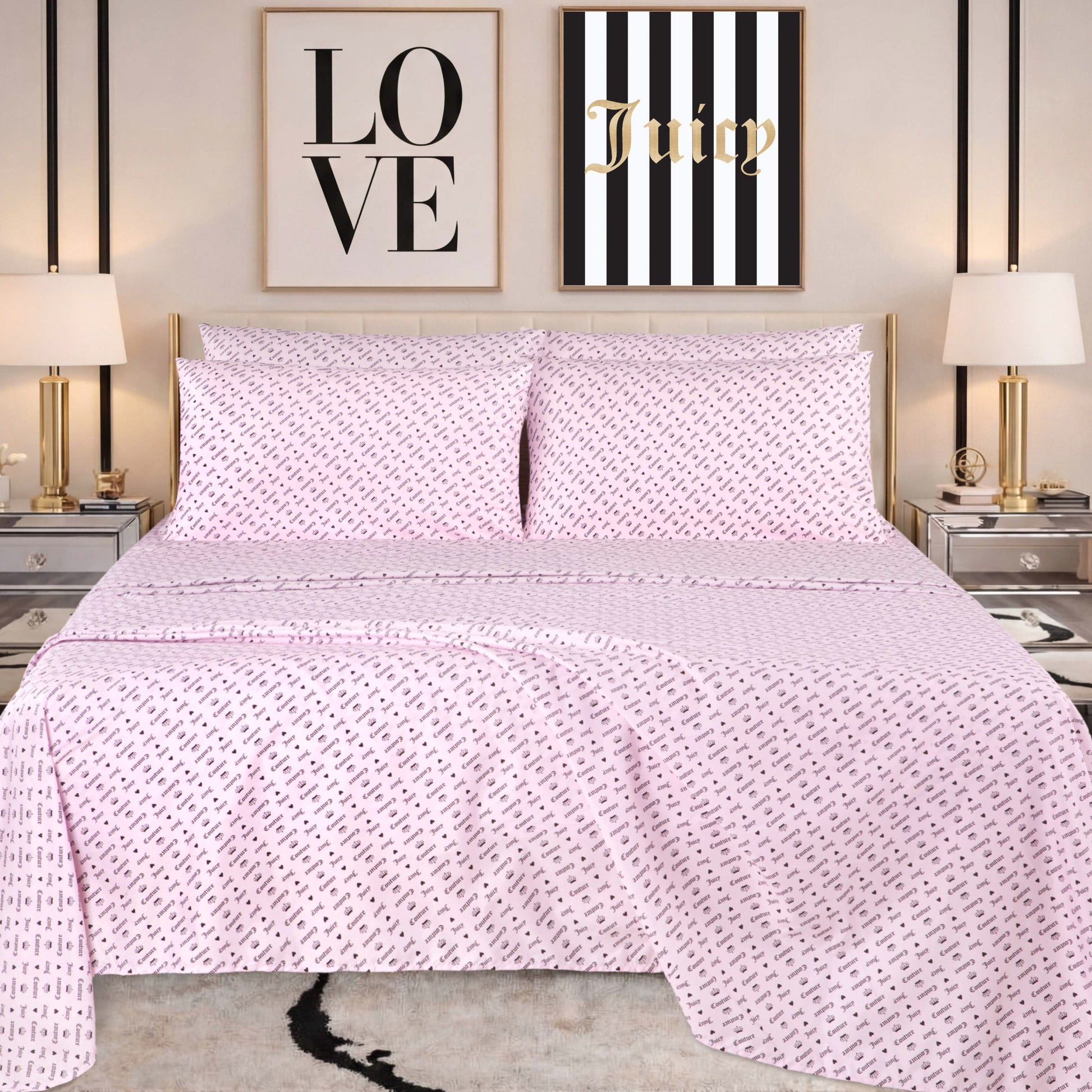 A neatly made bed with pink patterned bedding, featuring a Microfiber Sheet Set With Extra Pillowcases for added style, is flanked by two lamps on mirrored nightstands. Above the bed are two wall art pieces: one says LOVE and the other says Juicy on black and white stripes.
