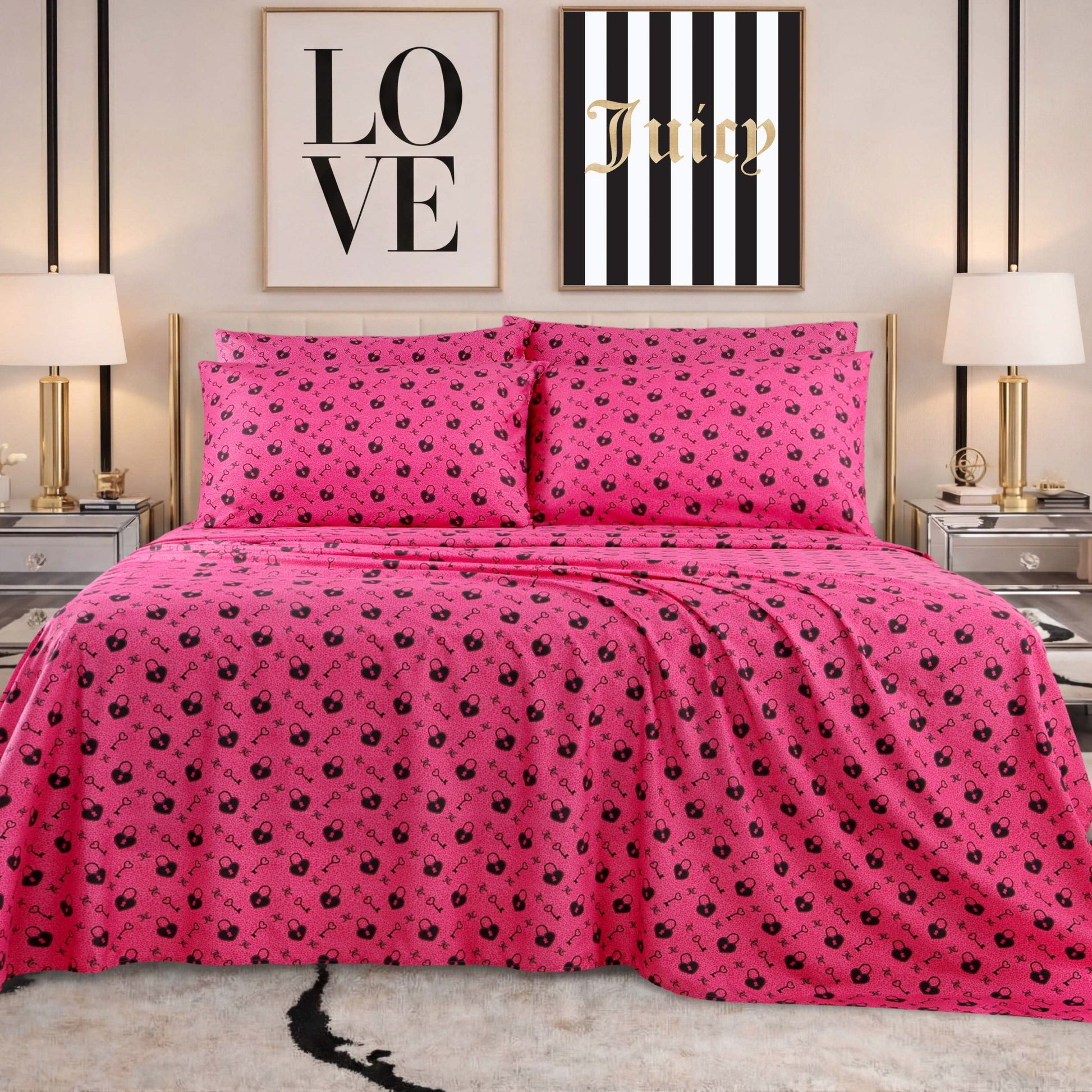 A bed adorned with a vibrant pink Microfiber Sheet Set With Extra Pillowcases, featuring playful Hello Kitty sheets and pillowcases, is flanked by two lamps on mirrored nightstands. Above the bed hang two framed prints—one that reads “LOVE,” and the other “Juicy” with bold black-and-white stripes.