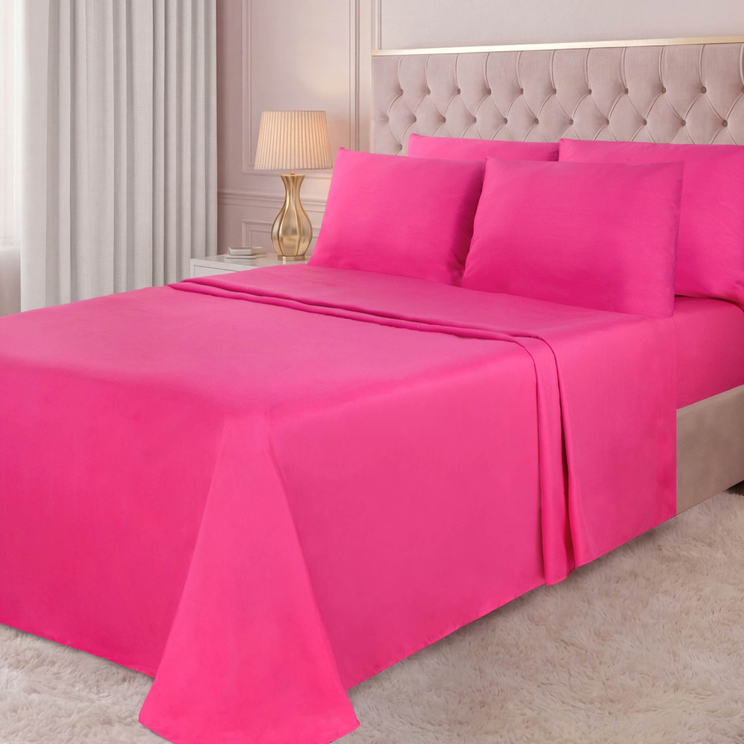 A neatly made bed featuring the Microfiber Sheet Set With Extra Pillowcases in bright pink, set in a bedroom with a tufted beige headboard, a gold lamp, light walls, and a white shag rug.