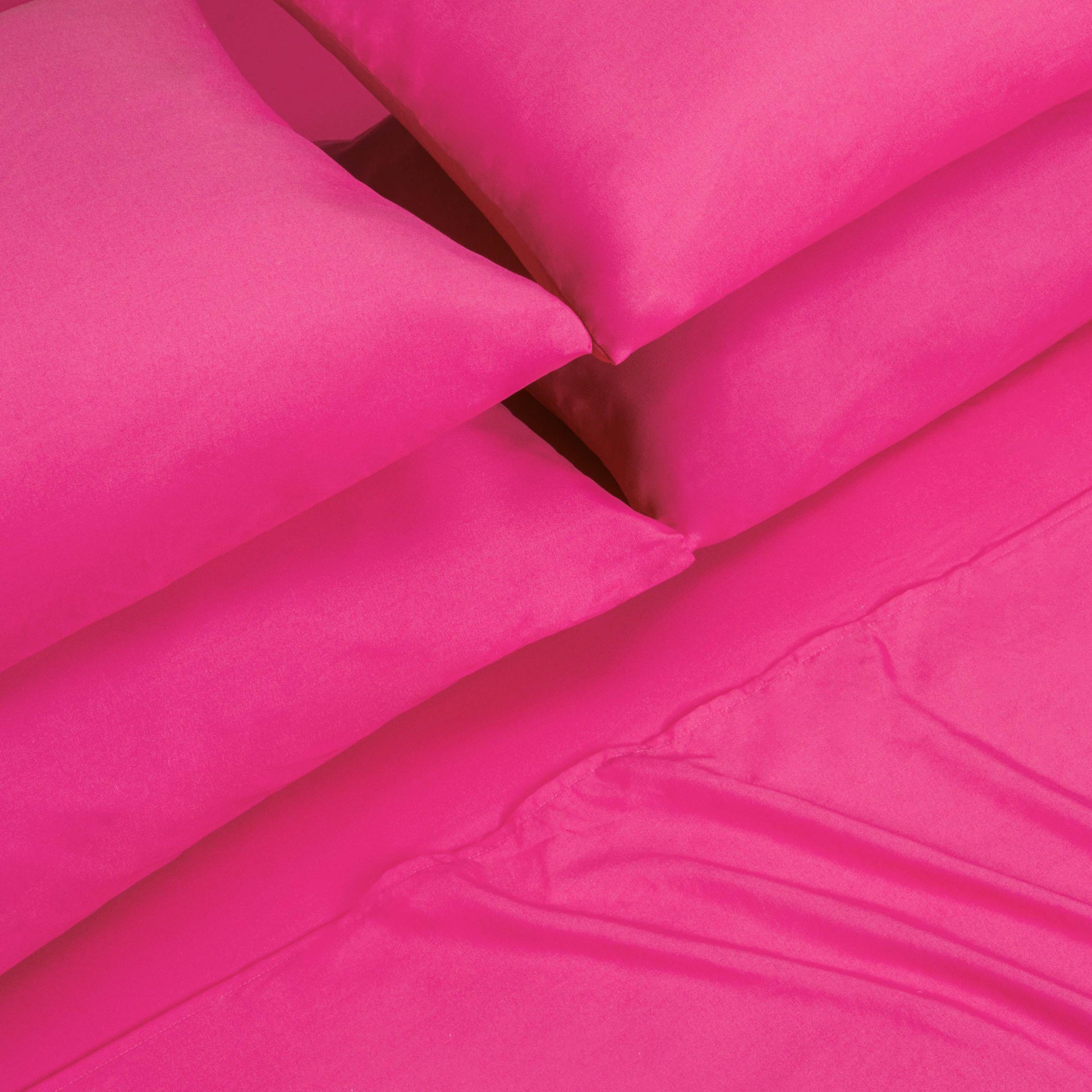 Four bright pink pillows are stacked next to each other on top of a matching pink Microfiber Sheet Set With Extra Pillowcases, showcasing a vibrant and colorful luxury bedding ensemble.