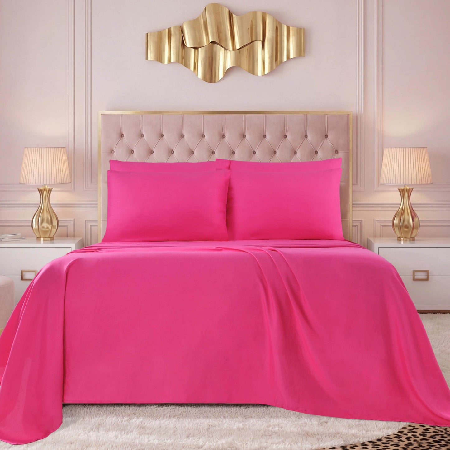 A bed dressed in the bright pink Microfiber Sheet Set With Extra Pillowcases, along with matching pillows, a beige tufted headboard, gold wall art, two gold lamps on white nightstands, and a cream-colored rug complete the look of this modern bedroom with luxury bedding.