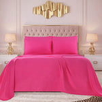 A bed dressed in the bright pink Microfiber Sheet Set With Extra Pillowcases, along with matching pillows, a beige tufted headboard, gold wall art, two gold lamps on white nightstands, and a cream-colored rug complete the look of this modern bedroom with luxury bedding.