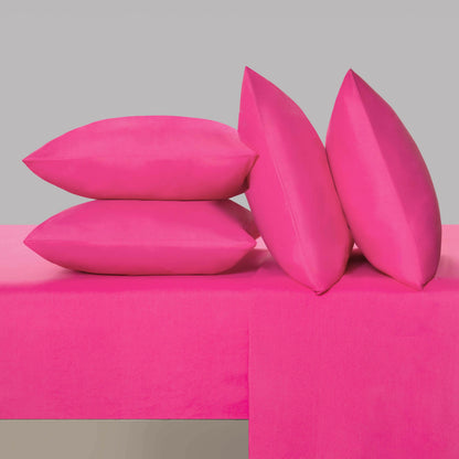 Four bright pink pillows from the Microfiber Sheet Set With Extra Pillowcases are arranged on a matching pink surface and background. Two pillows are stacked horizontally while two stand upright, leaning stylishly against the stack—creating a chic look reminiscent of luxury bedding or a bold designer accent.