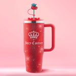 Here’s a rewritten version of your sentence using the product data: A Diamond Bling Stainless Steel Tumbler with Handle and Straw, 30 oz, in red, adorned with a crown and Juicy Couture logo. The lid is fitted with a metal straw topped by a cherry decoration, set against a pink background that accentuates the tumbler's glamorous rhinestone design.