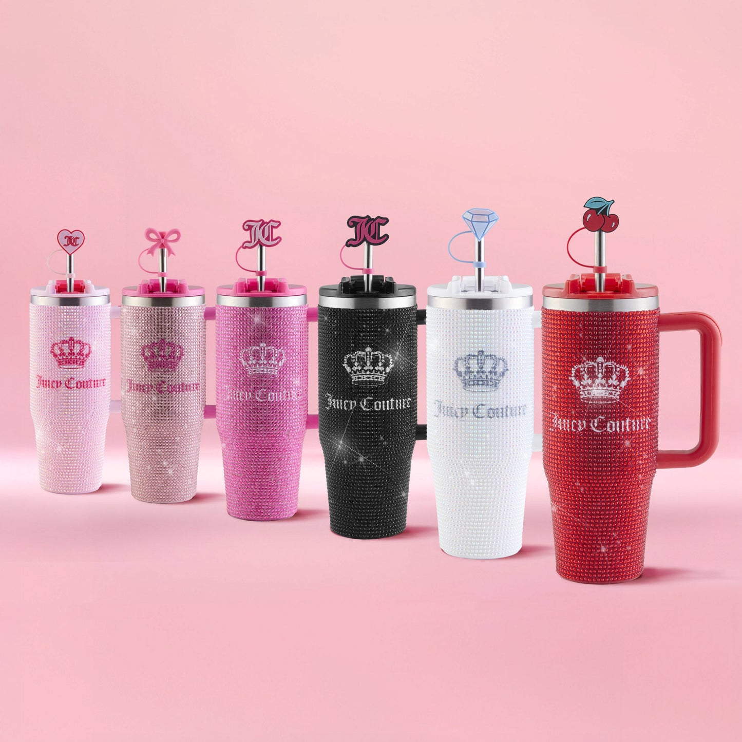 Six Diamond Bling Stainless Steel Tumblers with Handle and Straw, 30 oz, are arranged in a row on a pink surface with a pink background. The tumblers showcase a jeweled design with playful toppers and come in white, pink, red, and black colors.