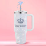 A dazzling Diamond Bling Stainless Steel Tumbler with Handle and Straw, 30 oz, embellished with sparkling rhinestones, a crown logo, white handle, and a blue diamond-shaped straw topper is showcased against a pink background. This glamorous tumbler elevates your everyday drinks with its eye-catching design.