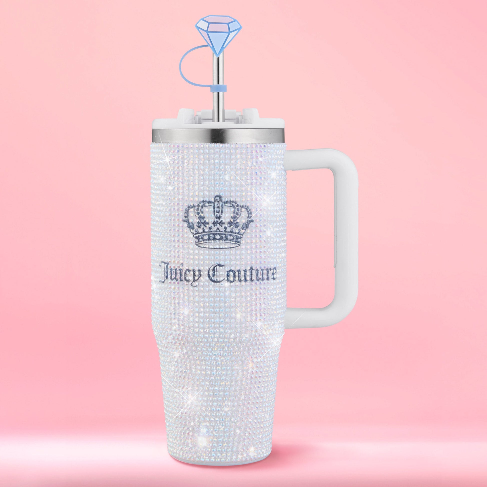 A dazzling Diamond Bling Stainless Steel Tumbler with Handle and Straw, 30 oz, embellished with sparkling rhinestones, a crown logo, white handle, and a blue diamond-shaped straw topper is showcased against a pink background. This glamorous tumbler elevates your everyday drinks with its eye-catching design.