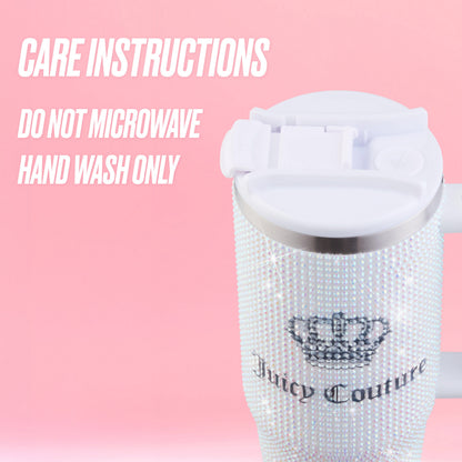 The Diamond Bling Stainless Steel Tumbler with Handle and Straw, 30 oz by Juicy Couture shimmers with sparkling rhinestones and features a white lid, set against a pink background. Text reads: “Care instructions: Do not microwave. Hand wash only.”.