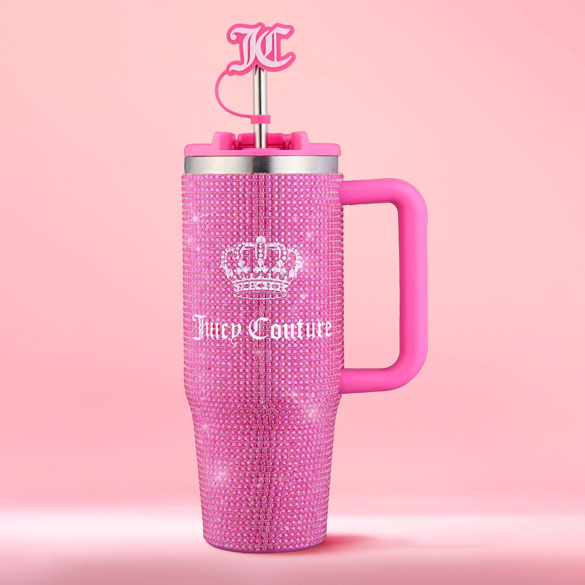 Introducing the Diamond Bling Stainless Steel Tumbler with Handle and Straw, 30 oz—a pink tumbler adorned with rhinestone accents, Juicy Couture and crown logos, a chunky pink handle, and a straw topped with a JC logo, set against a vibrant pink background.