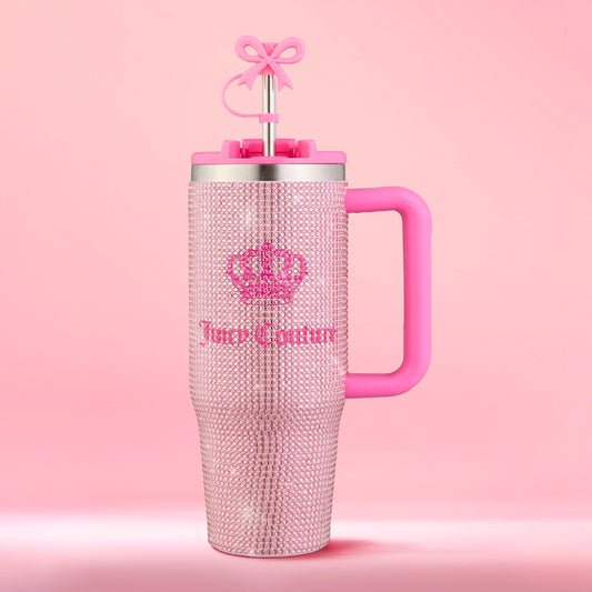 Introducing the Diamond Bling Stainless Steel Tumbler with Handle and Straw, 30 oz—a pink tumbler dazzling with rhinestones, adorned with a crown and the Juicy Couture logo. This glamorous cup shines brilliantly, featuring a sturdy pink handle and a straw topped by a cute pink bow, all set against a perfectly matching pink background.