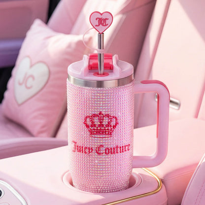 A Diamond Bling Stainless Steel Tumbler with Handle and Straw, 30 oz, sparkling with dazzling crystals, sits in a pink car cupholder. The tumbler comes in pink and features a crown logo along with a heart-shaped straw topper adorned with “JC.” A coordinating pink pillow rests on the car seat, completing the glamorous look.