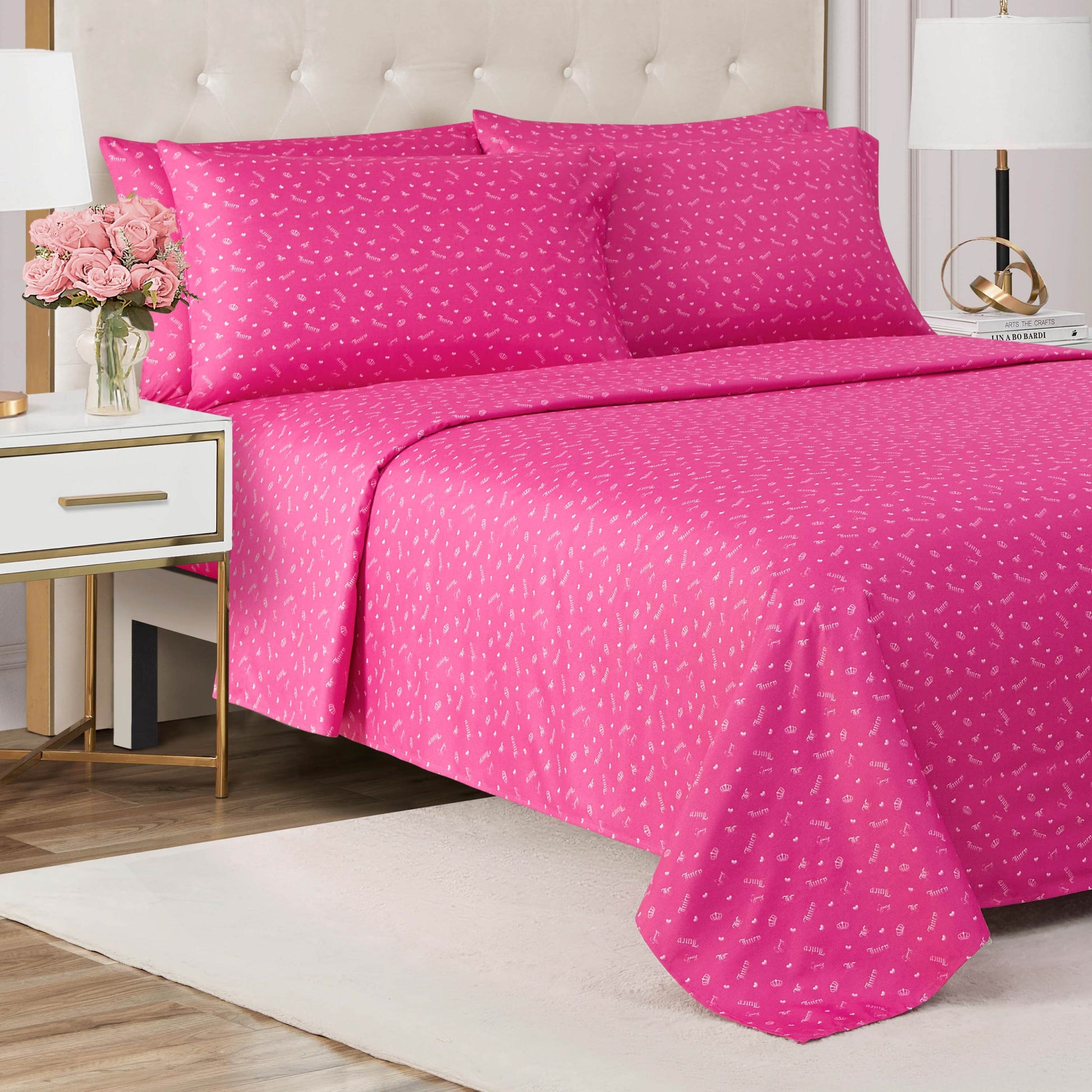 A stylish bedroom features a bed dressed in the Microfiber Sheet Set With Extra Pillowcases, adorned with small white hearts. A tufted headboard, nightstands with lamps, and a vase of pink roses finish the chic look.
