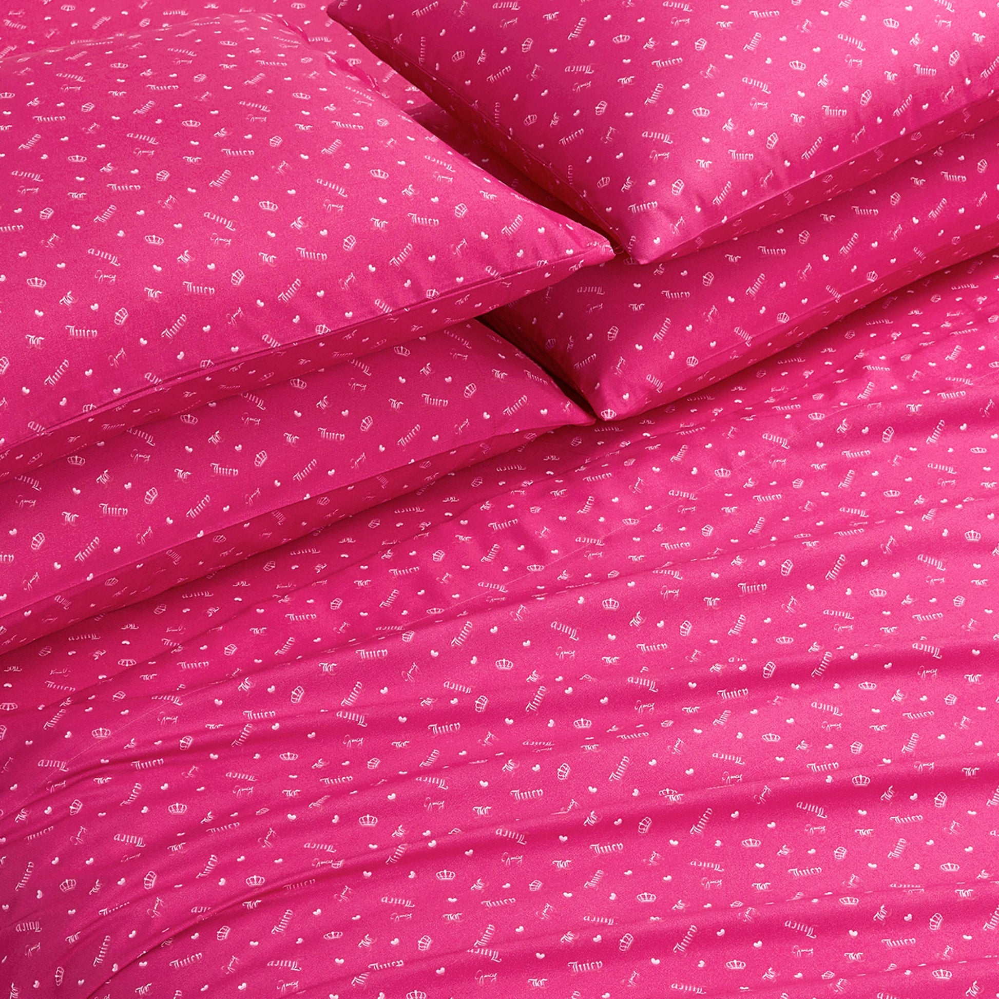 The Microfiber Sheet Set With Extra Pillowcases features bright pink bedding with playful white icons and words, arranged neatly on the bed. These ultra-soft sheets add a cheerful, inviting touch to any room.