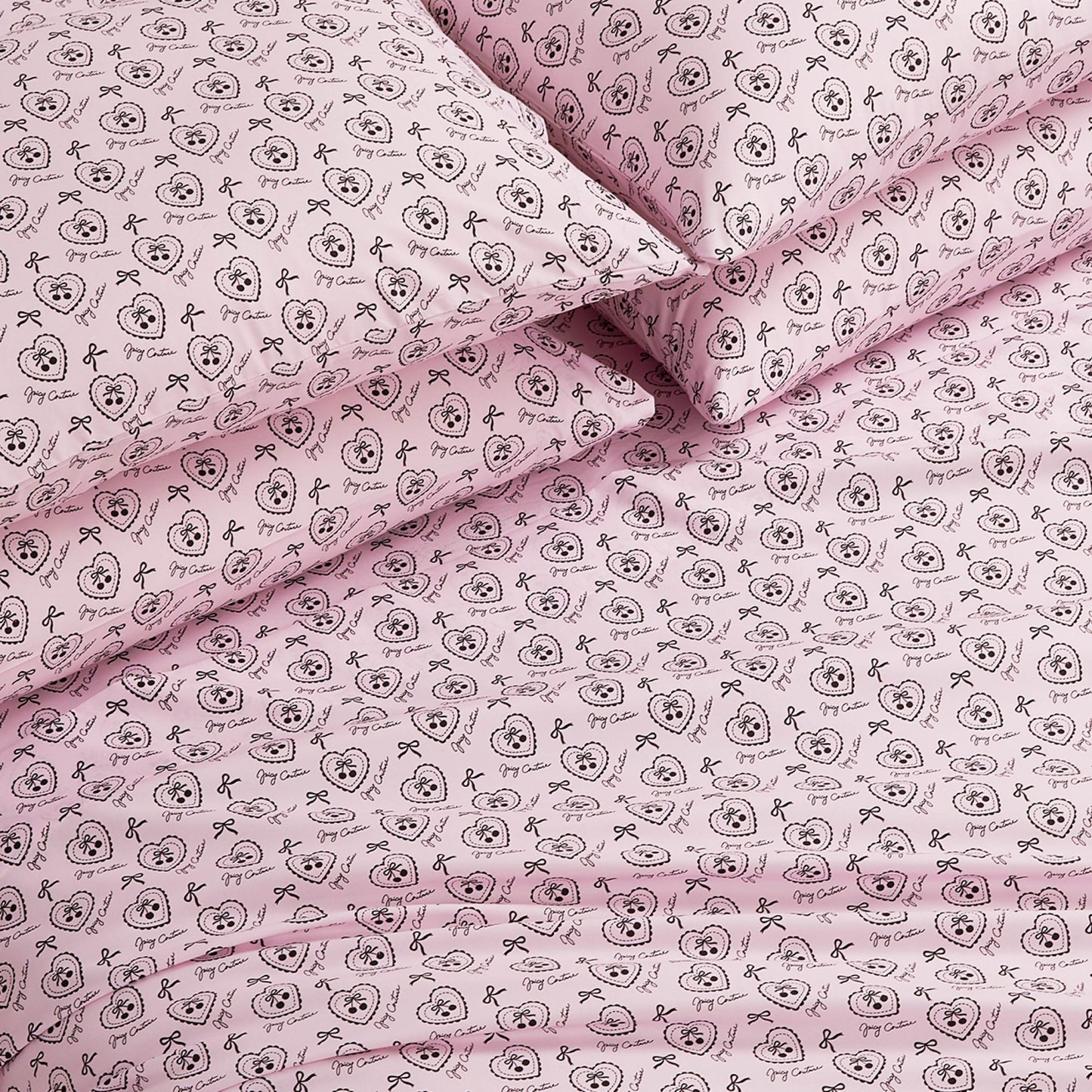 The Microfiber Sheet Set With Extra Pillowcases features a pink design with black outlined cartoon animal faces, bows, and decorative circles. This luxury bedding set looks soft, neatly arranged, and includes additional pillowcases.