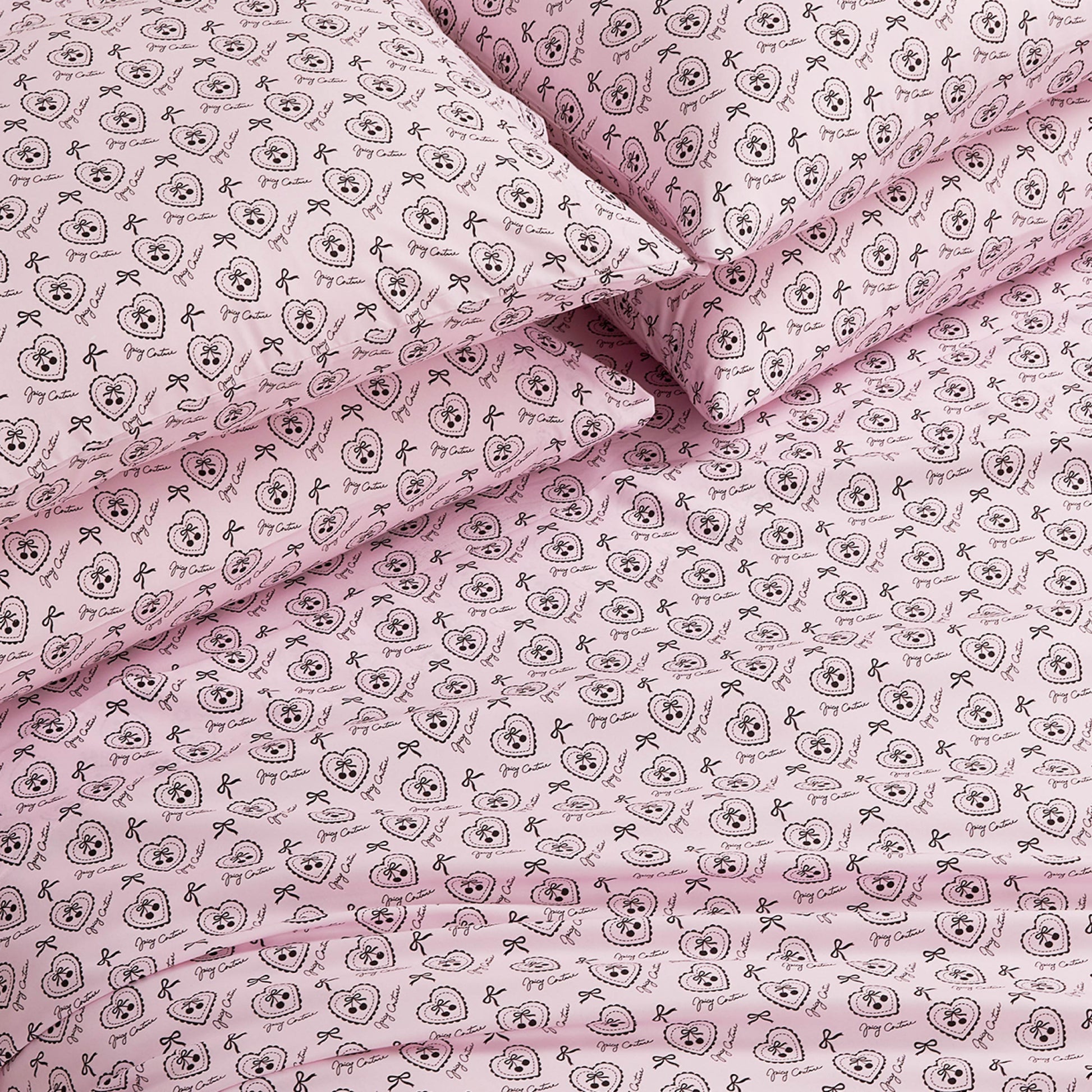The Microfiber Sheet Set With Extra Pillowcases features a pink design with black outlined cartoon animal faces, bows, and decorative circles. This luxury bedding set looks soft, neatly arranged, and includes additional pillowcases.