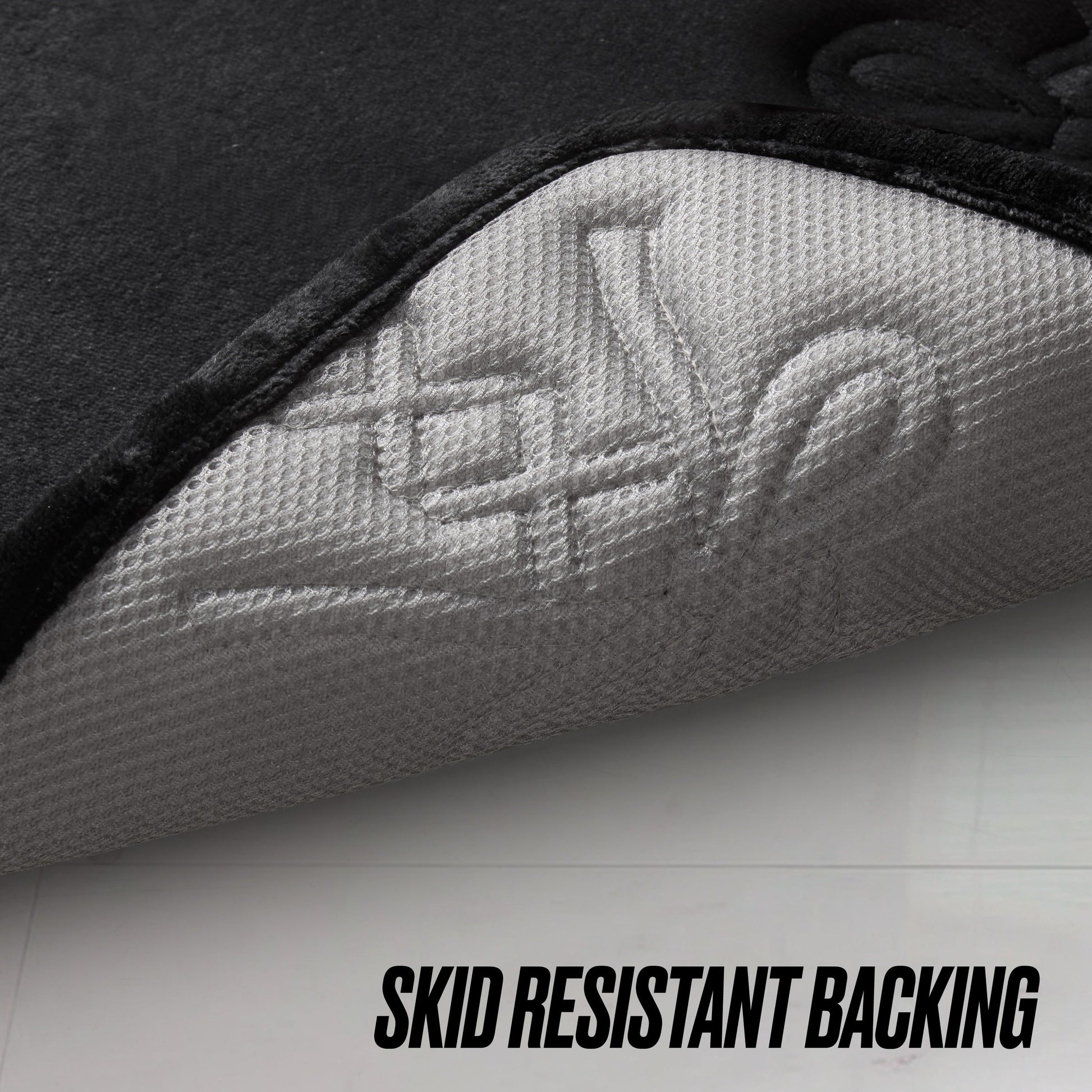 A close-up of the Quilted Memory Foam Bath Mat, 17" x 24", shows its corner lifted to display a textured white skid-resistant backing. Black text at the bottom reads SKID RESISTANT BACKING.