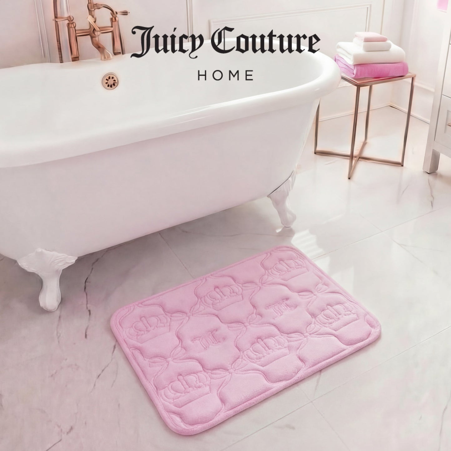A pink Quilted Memory Foam Bath Mat, 17" x 24", with crown patterns rests on a glossy white bathroom floor by a classic tub. Folded towels are stacked on a gold stand, creating the ultimate glam bathroom scene.