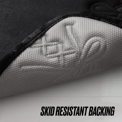 A close-up shows the corner of the Quilted Memory Foam Bath Mat 2-Piece Set lifted to reveal its textured, light gray backing. “SKID RESISTANT BACKING” is displayed below, emphasizing this set’s secure and safe design.