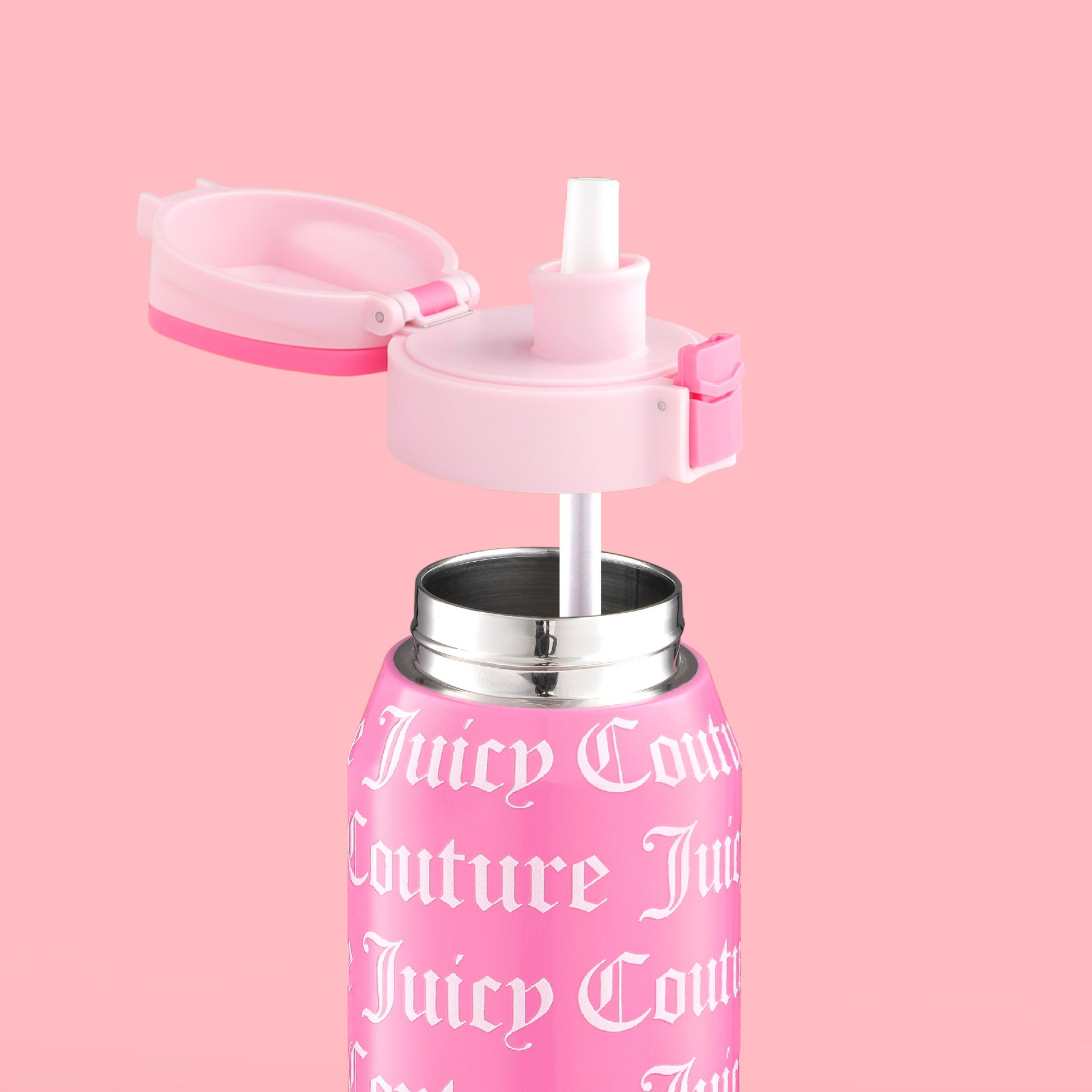 The Glam Getaway Hydration Stainless Steel Tumbler in pink features white Gothic-style text and logo, a flip-top lid, and a white straw. This 32oz Juicy Couture tumbler adds style and function to your daily hydration. Displayed on a matching pink background.