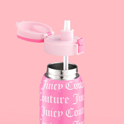 The Glam Getaway Hydration Stainless Steel Tumbler in pink features white Gothic-style text and logo, a flip-top lid, and a white straw. This 32oz Juicy Couture tumbler adds style and function to your daily hydration. Displayed on a matching pink background.