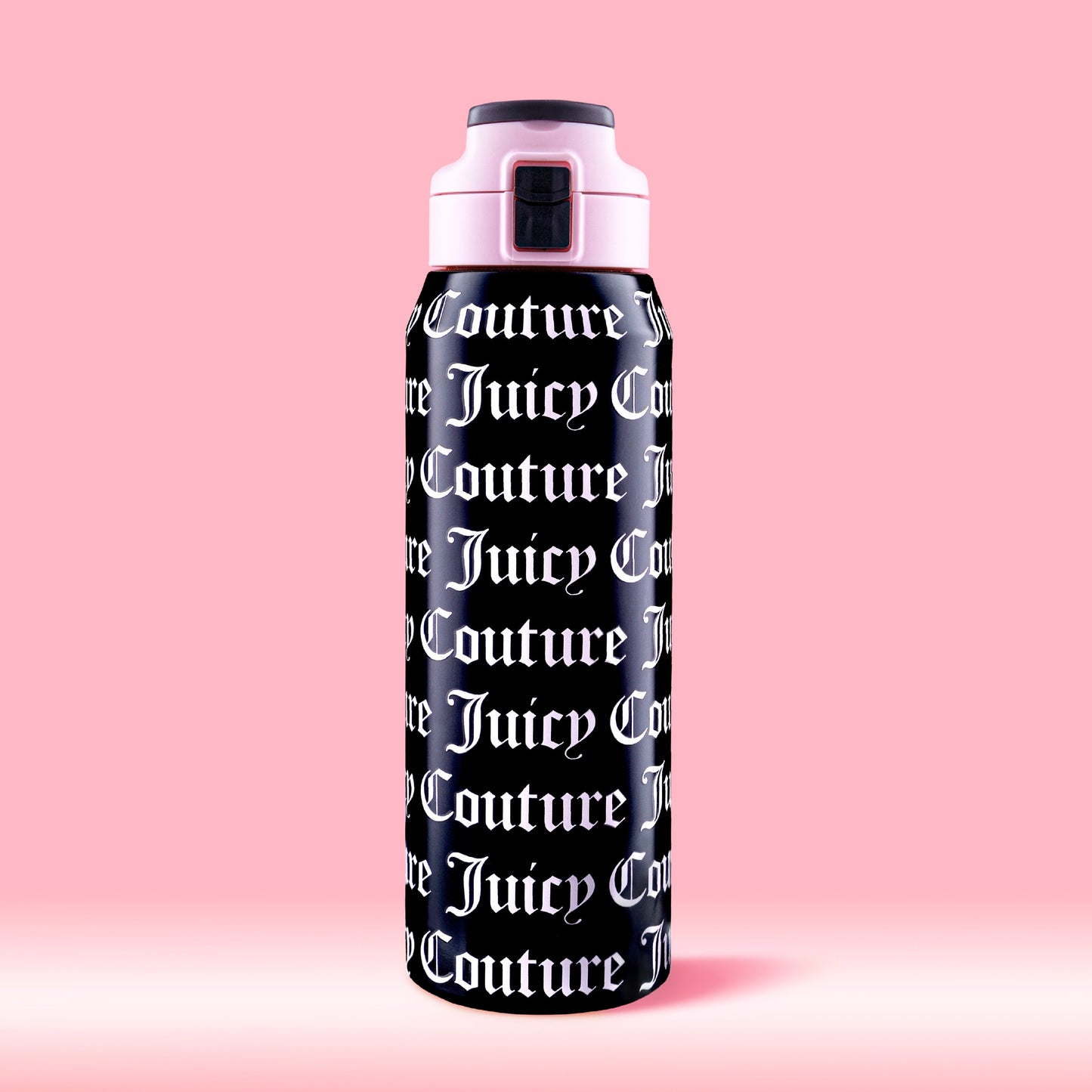 The Glam Getaway Hydration Stainless Steel Tumbler in black features bold white Juicy Couture logos across its surface, a pink and black lid, and is displayed against a solid pink background.