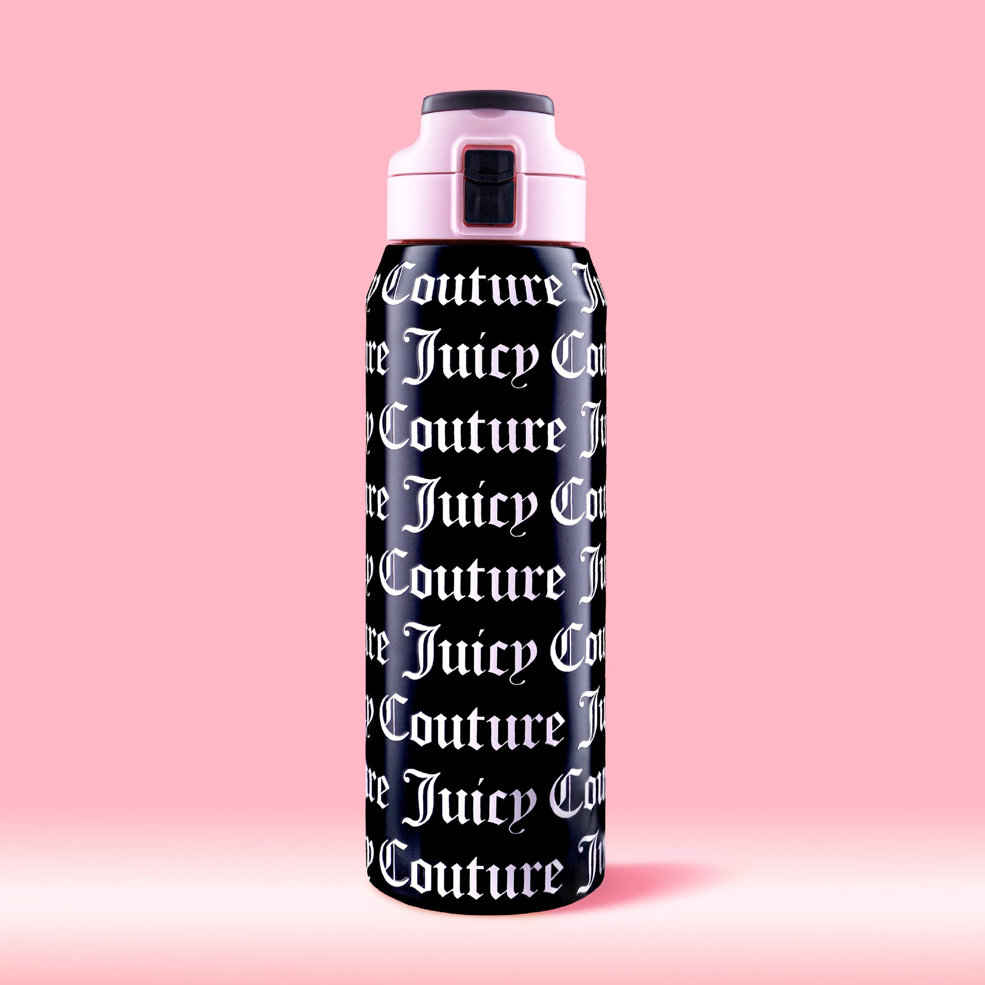 The Glam Getaway Hydration Stainless Steel Tumbler in black features bold white Juicy Couture logos across its surface, a pink and black lid, and is displayed against a solid pink background.